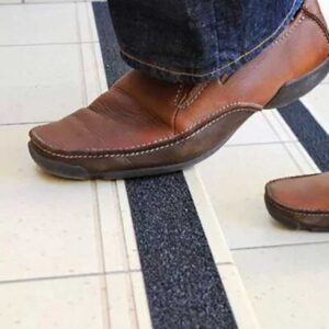 Noga čoveka staje na stepenik sa anti slip trakom za bolju sigurnost